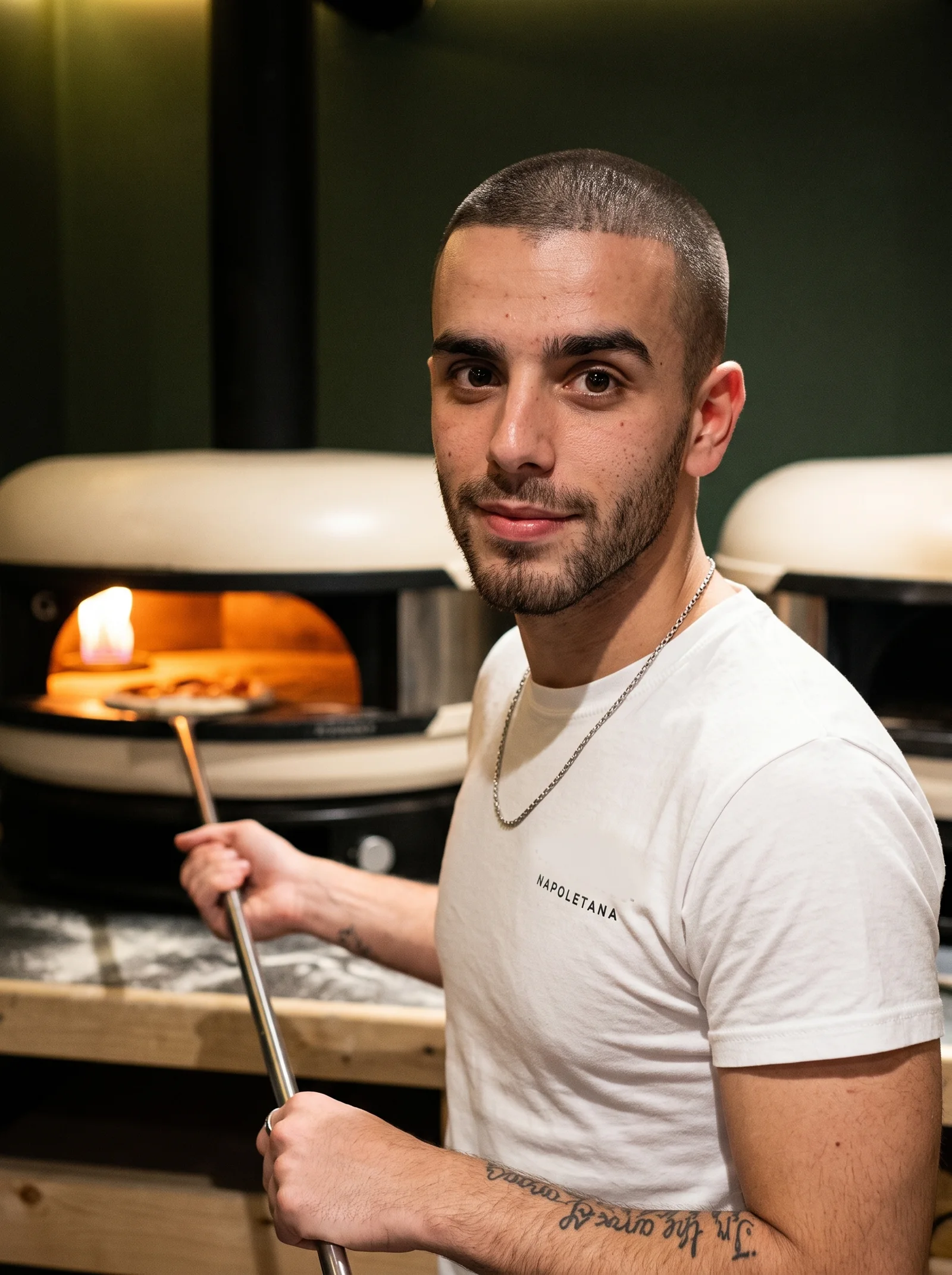 Brad at the two domed ovens, one glowing, holding a pizza peel